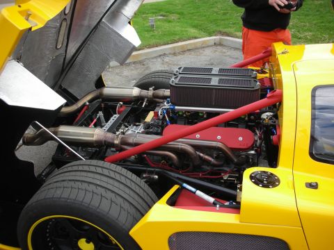 1998 Ford Crown Victoria - The engine bay of a yellow sports car is open, revealing its V8 engine and exhaust system.