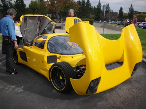 1998 Ford Crown Victoria - A bright yellow custom sports car is displayed with its hoods open, revealing its mechanical components.