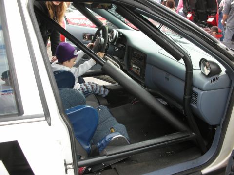 1998 Ford Crown Victoria - Child sits in the driver's seat of a modified car with a roll cage installed.