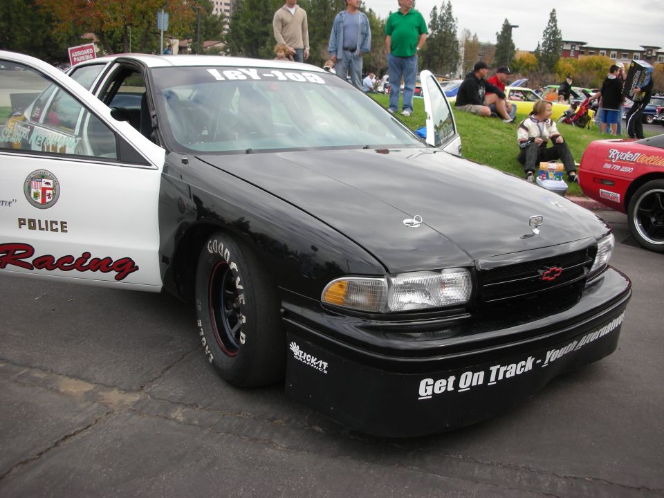 Black and white police racing car with doors open, drag tires, and racing decals