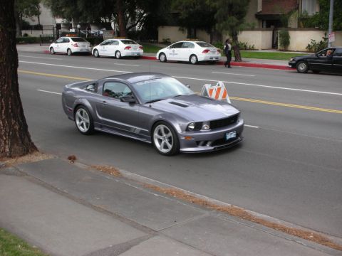 1998 Ford Crown Victoria - Gray 2005-2010 Ford Mustang Saleen with 'Saleen' decal on windshield.