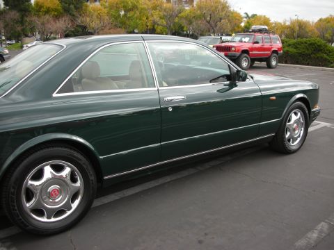 1998 Ford Crown Victoria - Photograph of a dark green Bentley coupe parked in a lot, showing its side profile and chrome wheels.