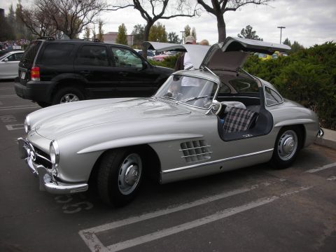 1998 Ford Crown Victoria - Photograph of a silver Mercedes-Benz 300SL Gullwing coupe with its gullwing door open at an outdoor car show.