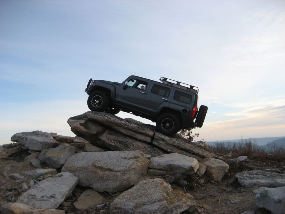 Dark gray Hummer H3 climbing over rocks on a steep incline.