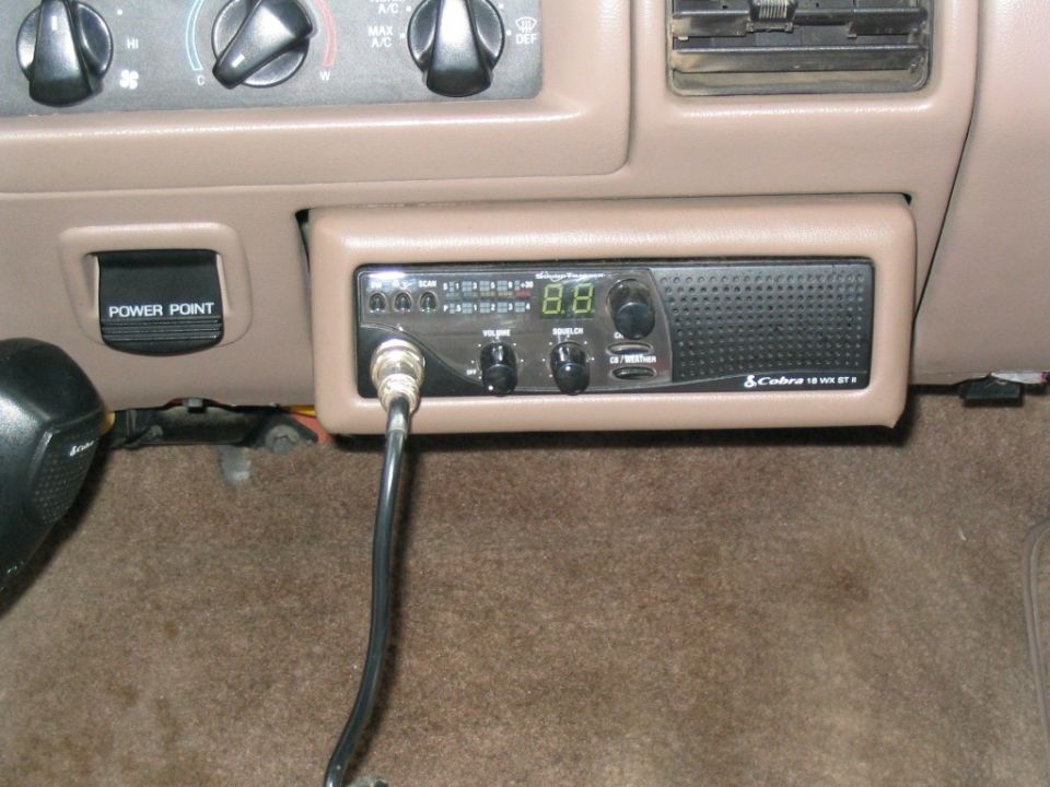 Cobra 18 WX ST II CB radio mounted in tan dash below HVAC controls with mic cord hanging down