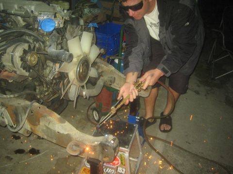 1990 Ford Bronco - Photograph of a person using a cutting torch on a vehicle frame, not a technical document.