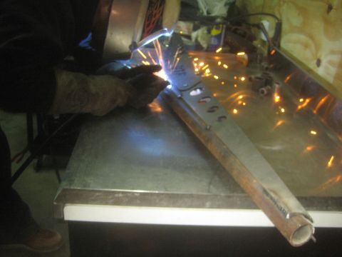 1990 Ford Bronco - Photograph of welding a fabricated steel tube assembly on a workbench, not a technical document.