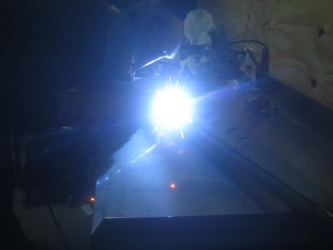 1990 Ford Bronco - Photograph of a bright welding arc fusing steel plate in a dark shop, not a document.