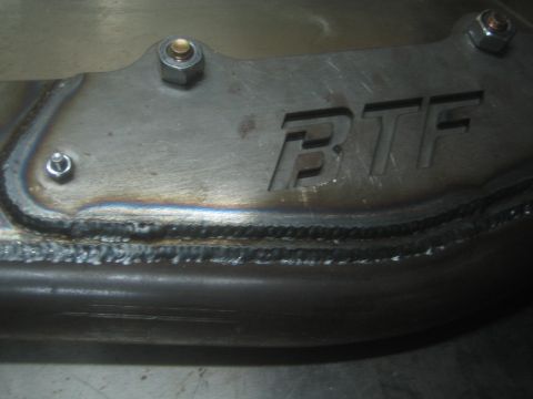 1990 Ford Bronco - Close-up photograph of a welded FTF-stamped steel bracket and weld bead, not a document.