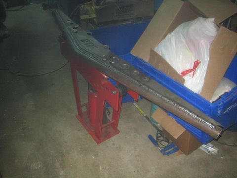 1990 Ford Bronco - Photograph of a fabricated FTF steel frame member supported on a jack stand, not a document.