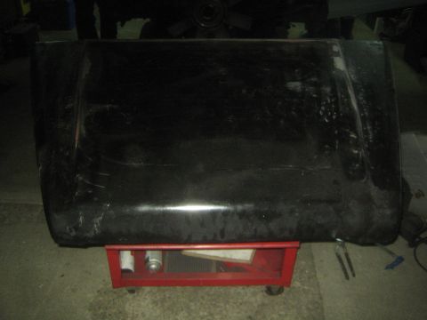 1987 Suzuki Samurai - Photo of a dark vehicle hood propped on a red rolling tool cart in a garage.