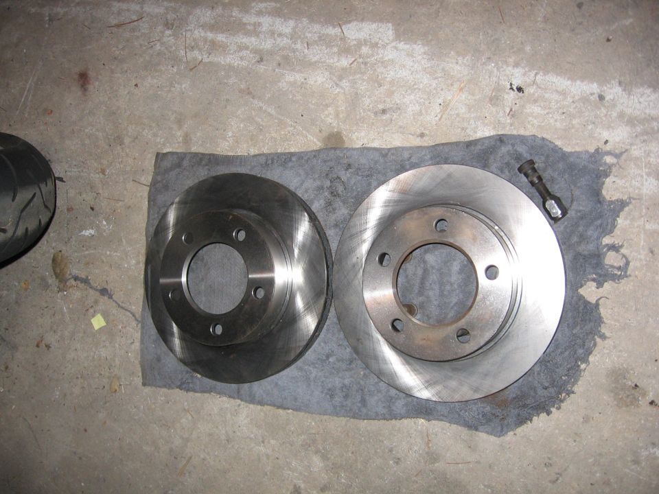 Two brake rotors laid on a rag on a concrete floor