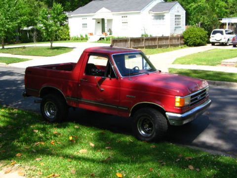 1991 Ford Bronco - A red 1987 Ford Bronco II is parked on the side of a street in front of a house.