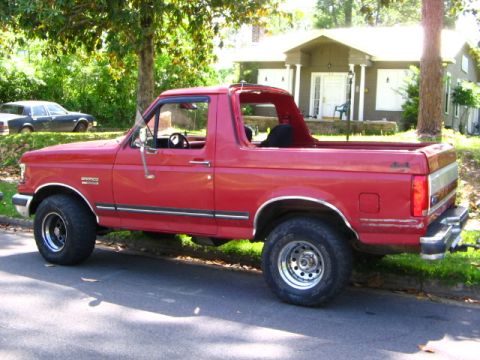 1991 Ford Bronco - This red 1991 Ford Bronco is parked on the side of a residential street.