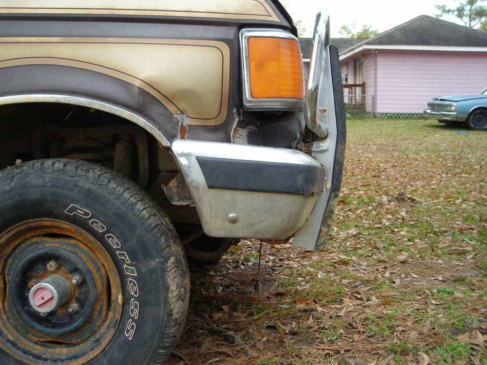 Close-up of damaged front fender and bumper on a brown and tan Ford Bronco.