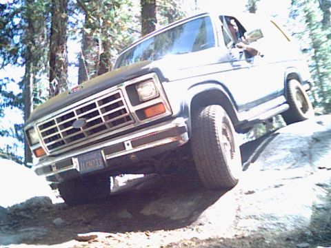 1985 Ford Bronco - This white SUV navigates a rocky trail, its grille clearly visible.