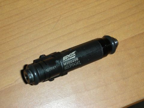 1998 Ford Crown Victoria - Photograph of a black Edge Racing fuel injector showing markings, resting on a wooden table.