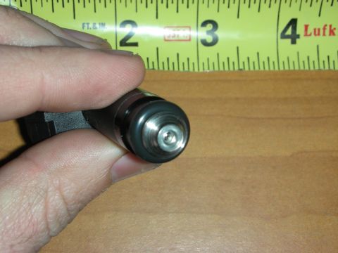1998 Ford Crown Victoria - Photograph of a hand holding the nozzle end of a fuel injector next to a tape measure.