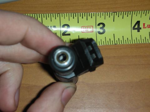 1998 Ford Crown Victoria - Photograph of a hand holding the electrical connector end of a fuel injector next to a tape measure.