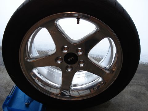 1998 Ford Taurus - A close-up, slightly angled shot of a chrome five-spoke wheel with a black SVT center cap. The wheel is mounted on a tire and is resting on…