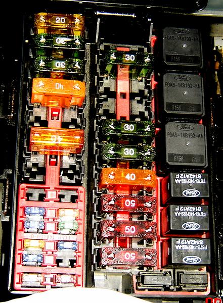 2007 Ford Mustang - A car's fuse box contains multiple fuses and relay modules, some bearing Ford branding.