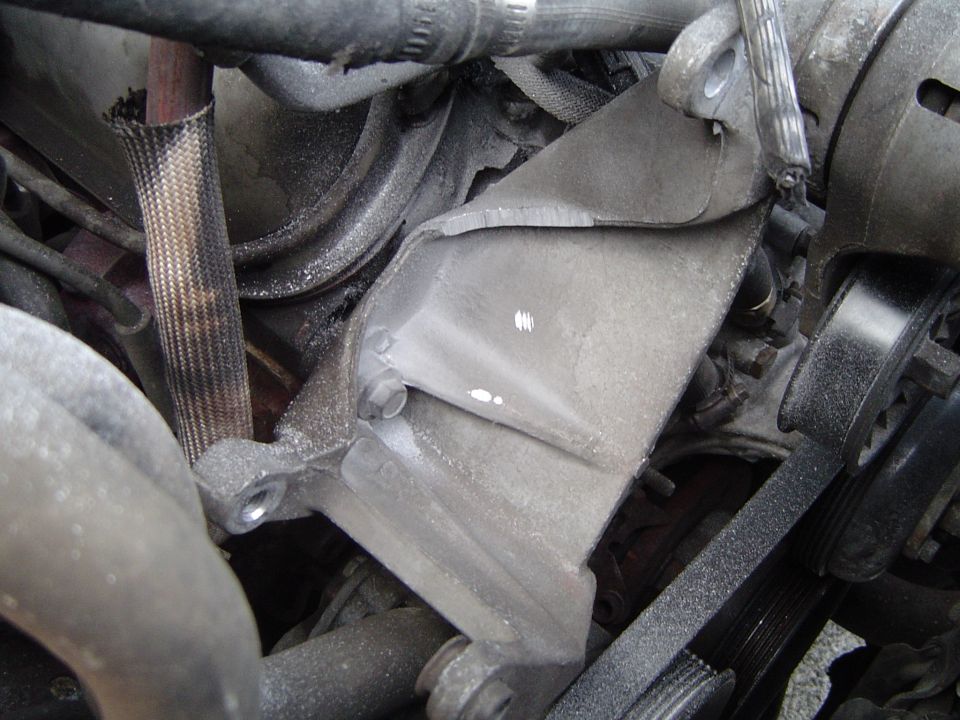 Cast aluminum accessory bracket on engine block with serpentine belt and braided-sleeve hose nearby