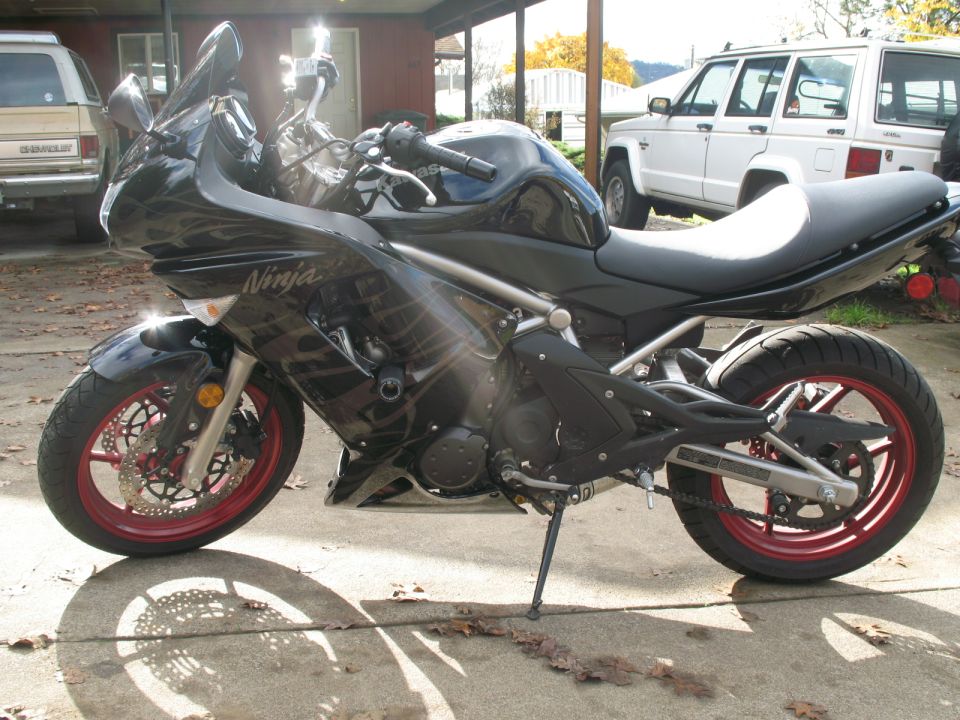 Black Kawasaki Ninja motorcycle with red rims parked on concrete.