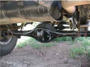 1979 Ford Bronco - Undercarriage view of a vehicle's rear axle and suspension system, showing exhaust components and a tire.