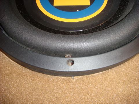1996 Ford Bronco - A close-up view of a black subwoofer speaker with a blue and yellow circular emblem visible at the top. Two small screw holes are visible a…