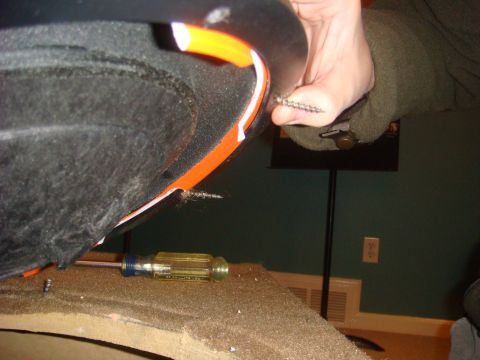 1996 Ford Bronco - A hand holds a screw, with a screwdriver visible nearby, suggesting interior work on a vehicle part.
