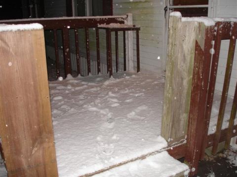 1996 Ford F-150 - A light snowfall covers a wooden porch and its railings.