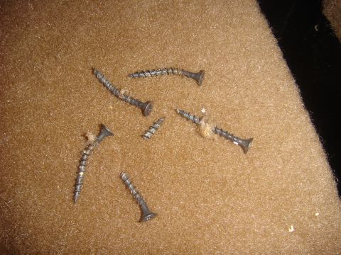 1996 Ford Bronco - Loose screws are scattered across the carpeted interior of a vehicle.