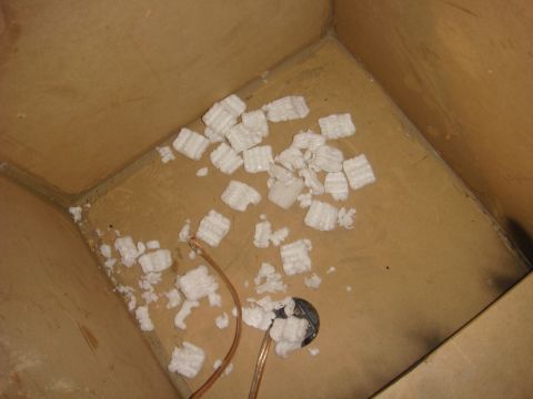 1996 Ford Bronco - Interior of a cardboard box filled with packing peanuts and wires, wires, with a black circular object visible.