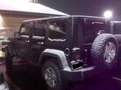 2008 Jeep Wrangler - A black 2008 Jeep Wrangler is seen covered in snow, viewed from the rear.