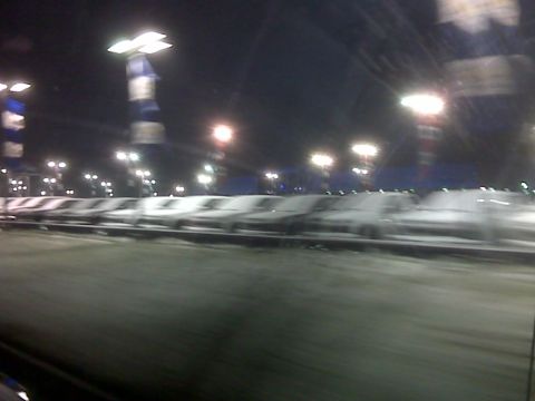 2008 Jeep Wrangler - A line of vehicles sits parked in a lot at night, illuminated by overhead lights.