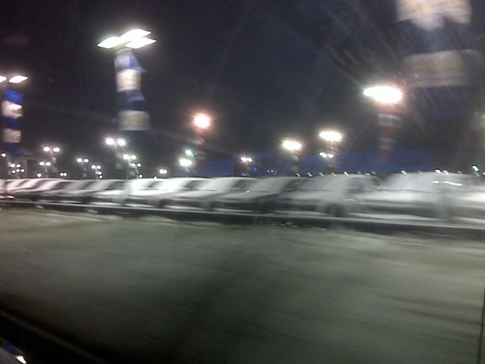 Cars parked in a lot at night under streetlights