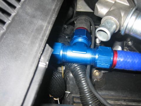 1996 Ford Thunderbird - Close-up of a blue aluminum T-fitting connecting flexible hoses in an engine bay.