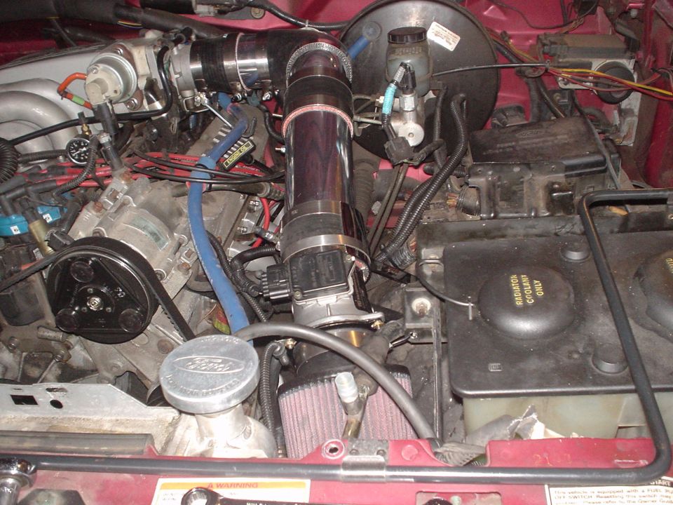 Engine bay showing aftermarket intake, air filter, and engine components. Radiator cap reads 'RADIATOR COOLANT ONLY'