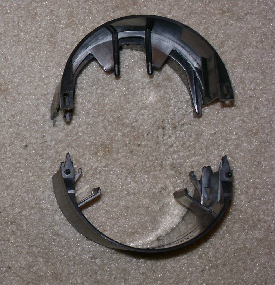 Two black plastic steering column shroud halves on carpet