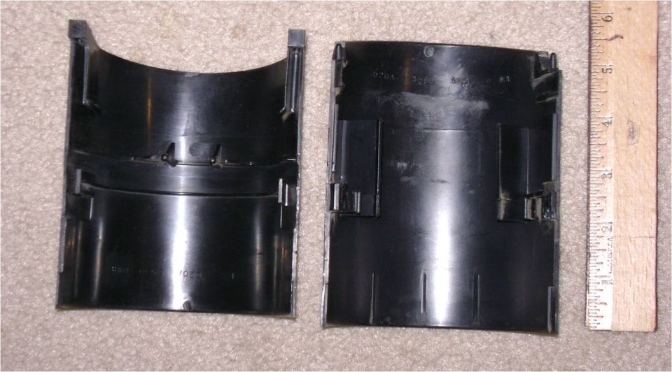Two black plastic shroud halves next to a ruler