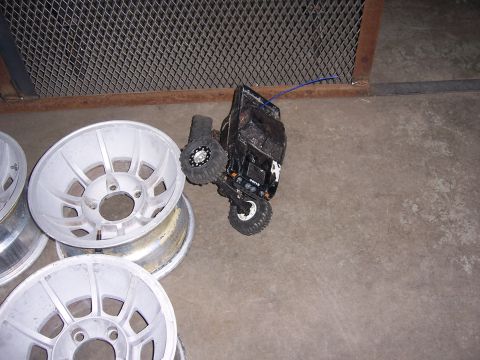 1979 Ford Bronco - A pile of car rims sits on the floor next to a small black remote control truck.
