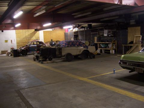 1979 Ford Bronco - Multiple vehicles are present in a garage, undergoing repair or restoration work.