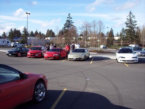 1991 Mitsubishi Eclipse - Several cars, including a 1991 Mitsubishi Eclipse, are parked in a lot on a sunny day.