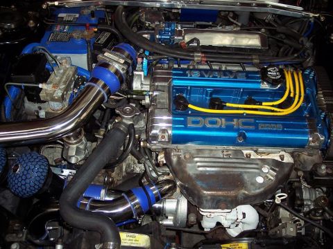 1991 Mitsubishi Eclipse - Engine bay details of a 1991 Mitsubishi Eclipse, a modified engine with custom blue accents and chrome piping.