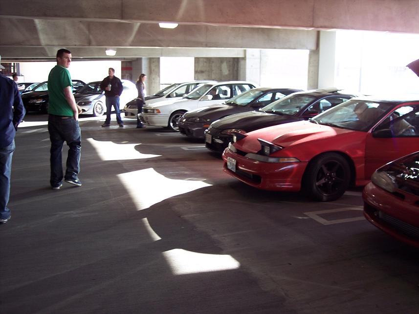 Red 1991 Mitsubishi Eclipse with pop-up headlights parked in a garage, other cars visible