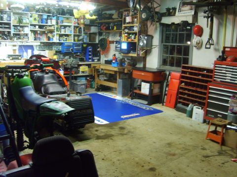 1995 Ford Bronco - A green and black Polaris snowmobile is parked in a cluttered garage workshop next to a red and black toolbox.