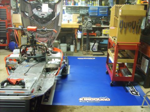 1995 Ford Bronco - A disassembled snowmobile, possibly a Suzuki King Quad, is parked in a garage or workshop. The engine and front body panels are removed, re…