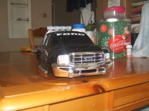 1988 Ford Bronco - A black Ford F-series pickup truck model with a chrome grille and bumper sits on a wooden table. The truck has four auxiliary lights mounte…