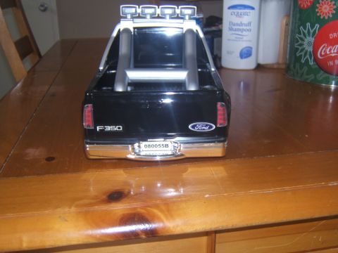 1988 Ford Bronco - The rear of a black Ford F-350 pickup truck model is shown on a wooden table. The truck has a chrome bumper and a license plate that reads…