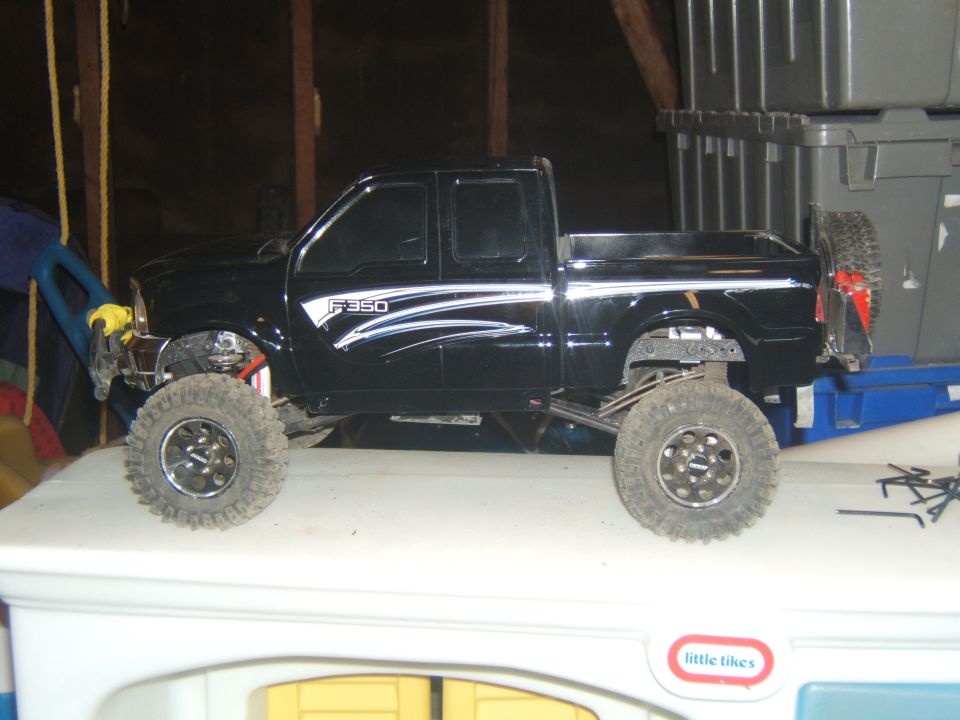 Black remote-controlled Ford F-350 pickup truck with lifted suspension and off-road tires.
